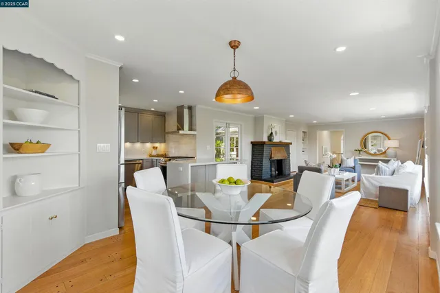 a view of a dining room and livingroom with furniture wooden floor a rug a fireplace and a chandelier