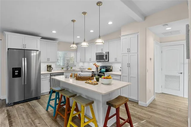 a kitchen with stainless steel appliances a dining table chairs stove refrigerator and cabinets