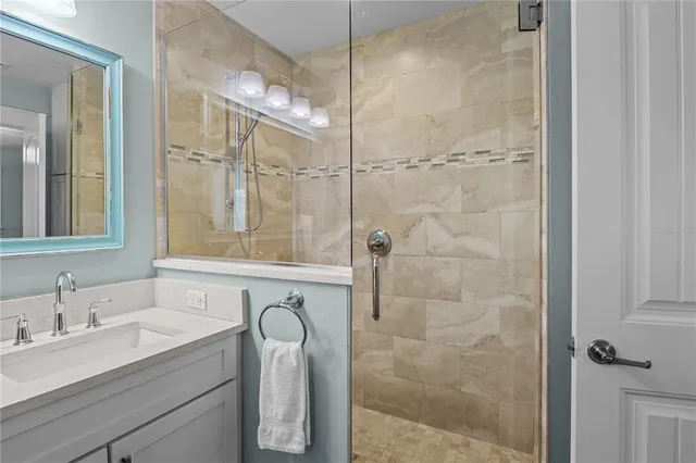 a bathroom with a granite countertop sink a mirror and shower