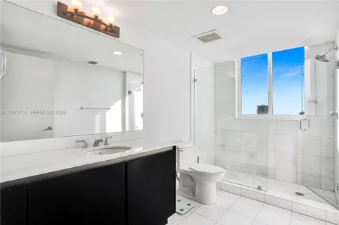 a bathroom with a double vanity sink toilet and shower