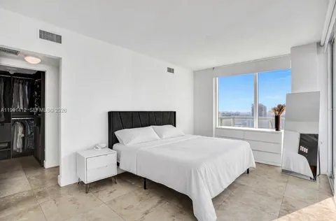 a bedroom with a bed and a refrigerator