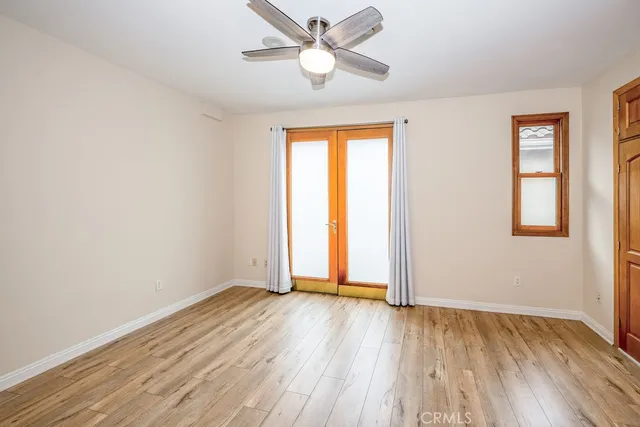 an empty room with wooden floor chandelier fan and windows