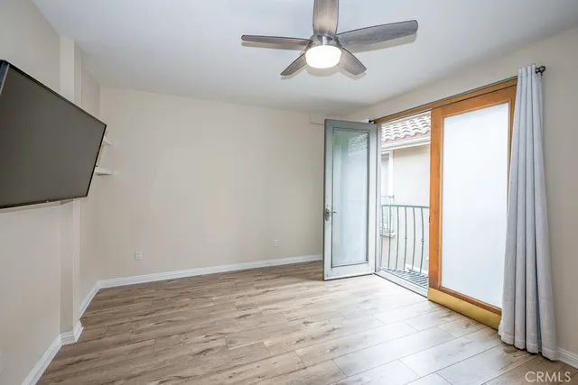 an empty room with wooden floor fan and windows