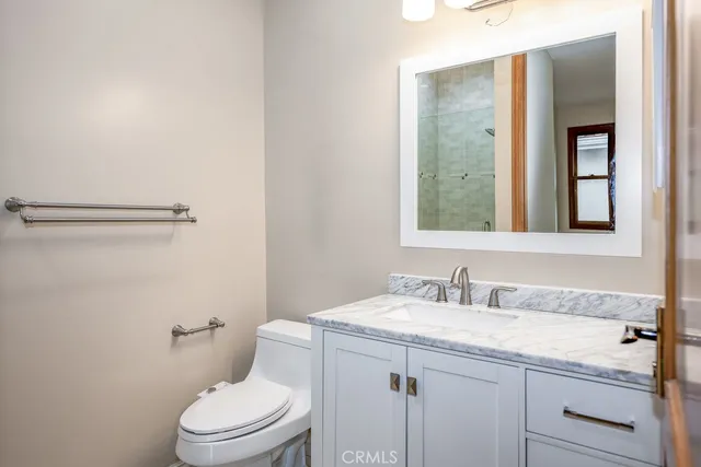 a bathroom with a granite countertop sink a toilet and a mirror