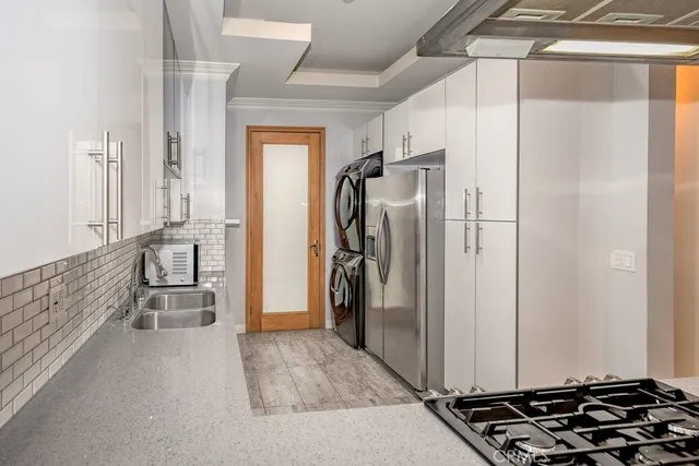 a walk in closet with wooden floor and a glass door shower