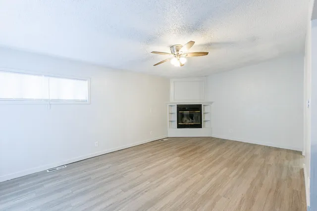 a view of a kitchen with a dishwasher a kitchen island hardwood floor and a window