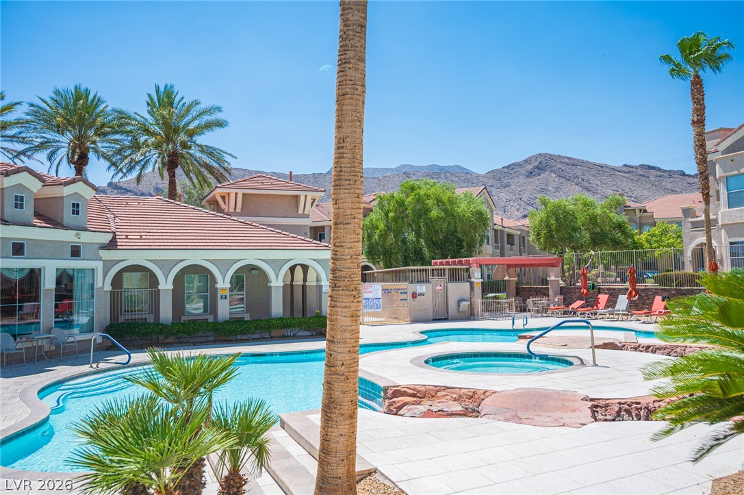 10550 West Alexander Road, Unit 2014 Las Vegas, NV 89129 - Photo 34 of 35 Desert oasis living with a sparkling pool and spa, framed by lush palm trees and mountain vistas.