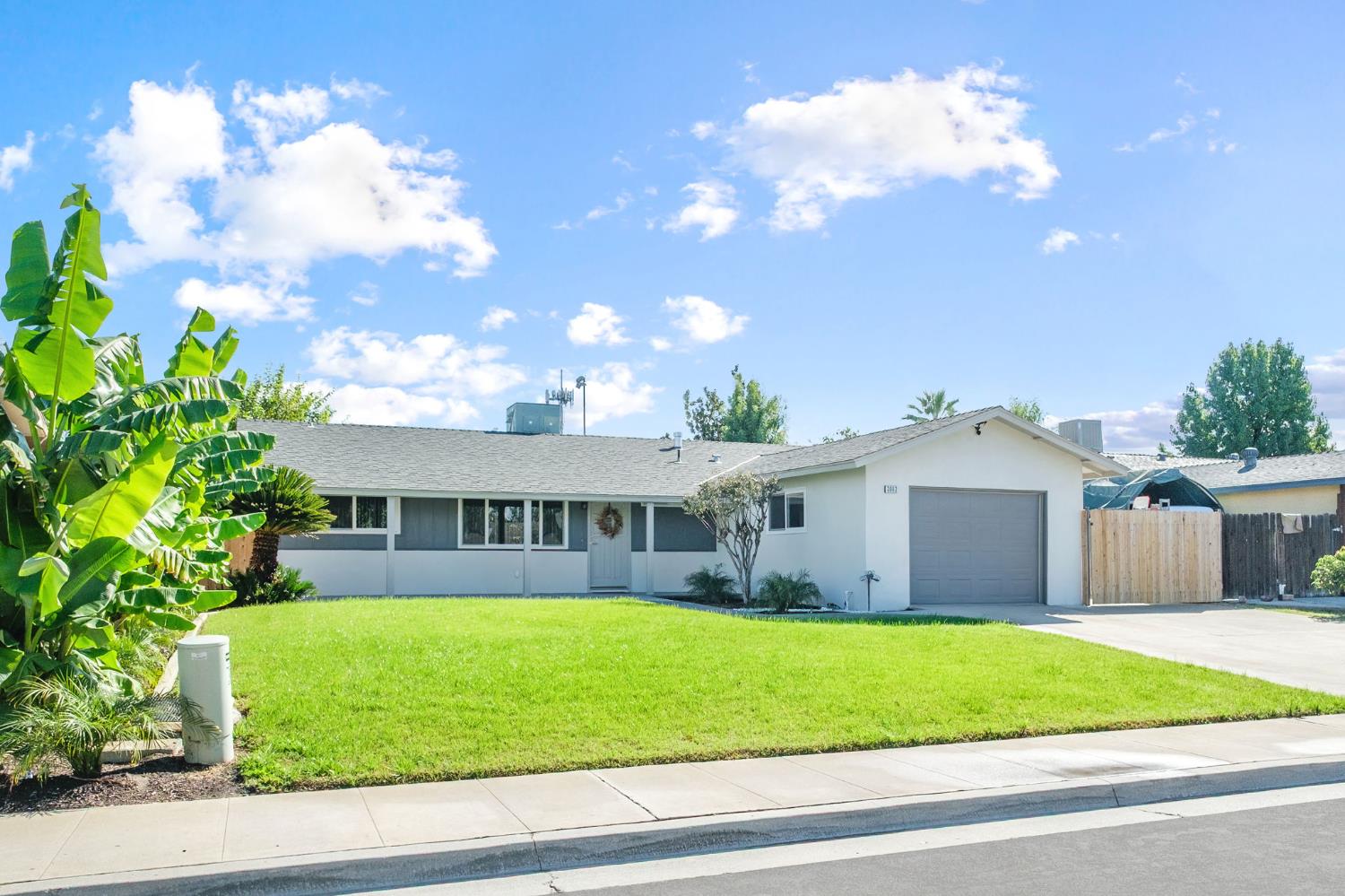 a view of a white house with a yard and plants