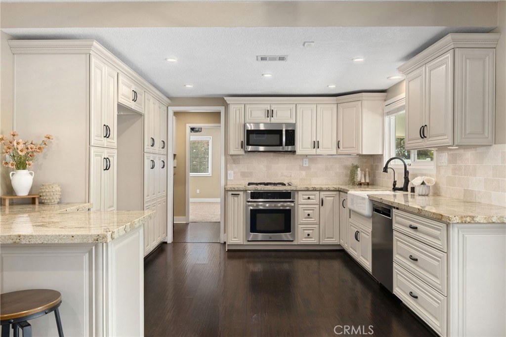 8729 Hillside Road Rancho Cucamonga, CA 91701 - Photo 17 of 66 a kitchen with stainless steel appliances granite countertop a stove top oven a sink dishwasher a refrigerator and a dining table with wooden floor