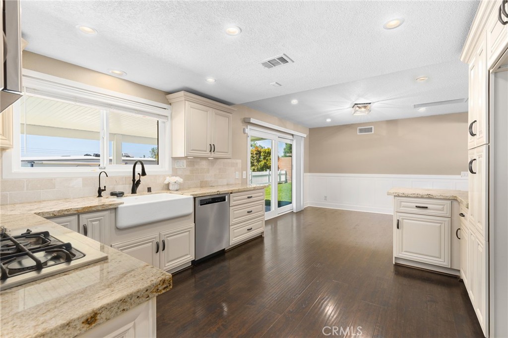 8729 Hillside Road Rancho Cucamonga, CA 91701 - Photo 20 of 66 a large kitchen with stainless steel appliances a stove a sink dishwasher and white cabinets with wooden floor