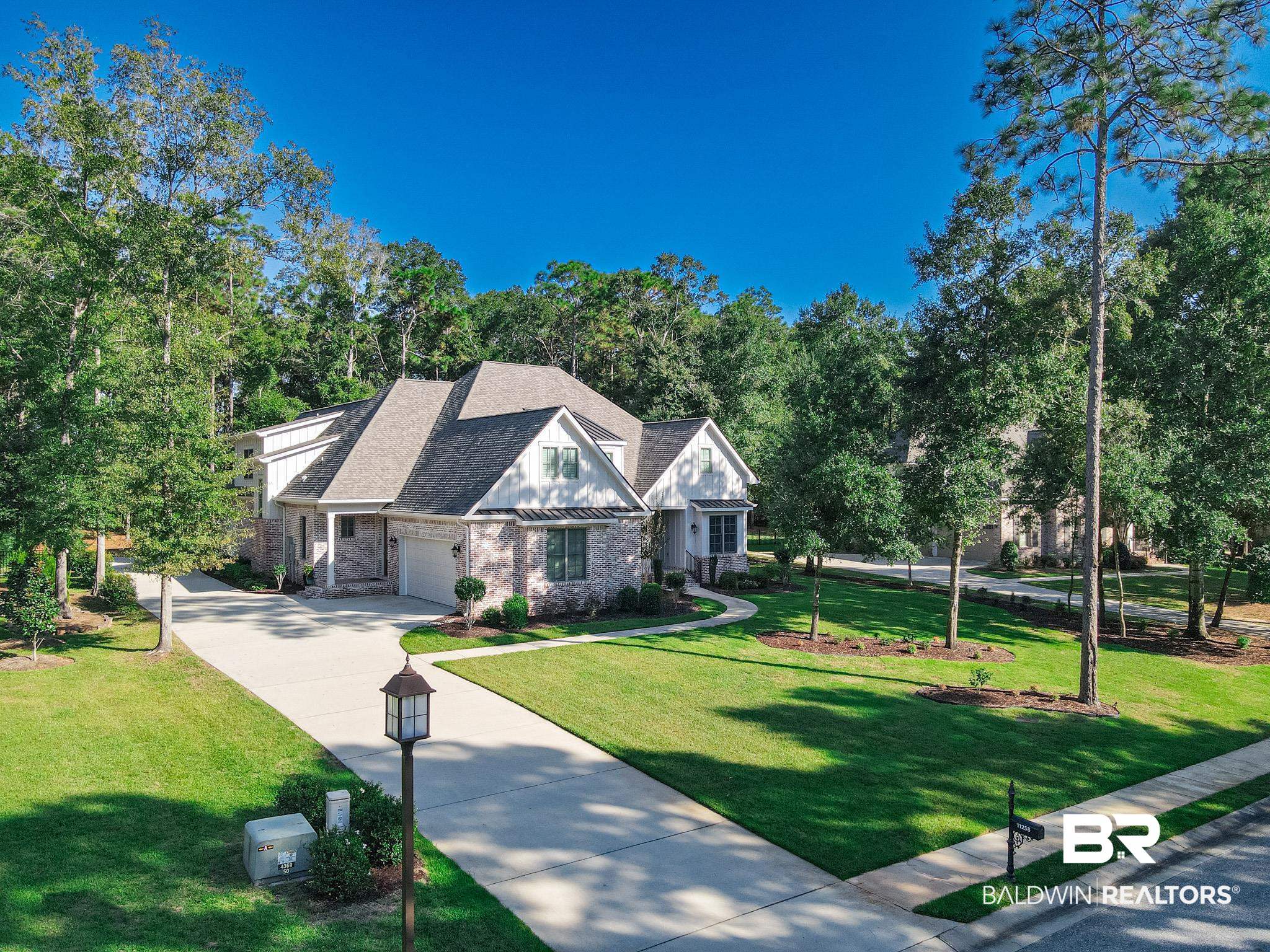 11258 Redfern Road Daphne, AL 36526 - Photo 1 of 44 View of front of house with a standing seam roof, concrete driveway, a metal roof, roof with shingles, and a front lawn