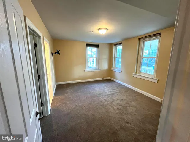 a view of an empty room with closet and a window