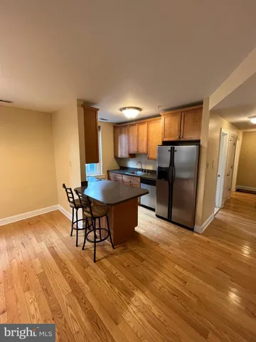 a kitchen with stainless steel appliances a dining table chairs stove refrigerator and cabinets