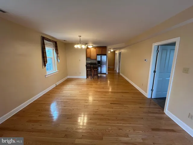 a view of empty room with dining room and wooden floor