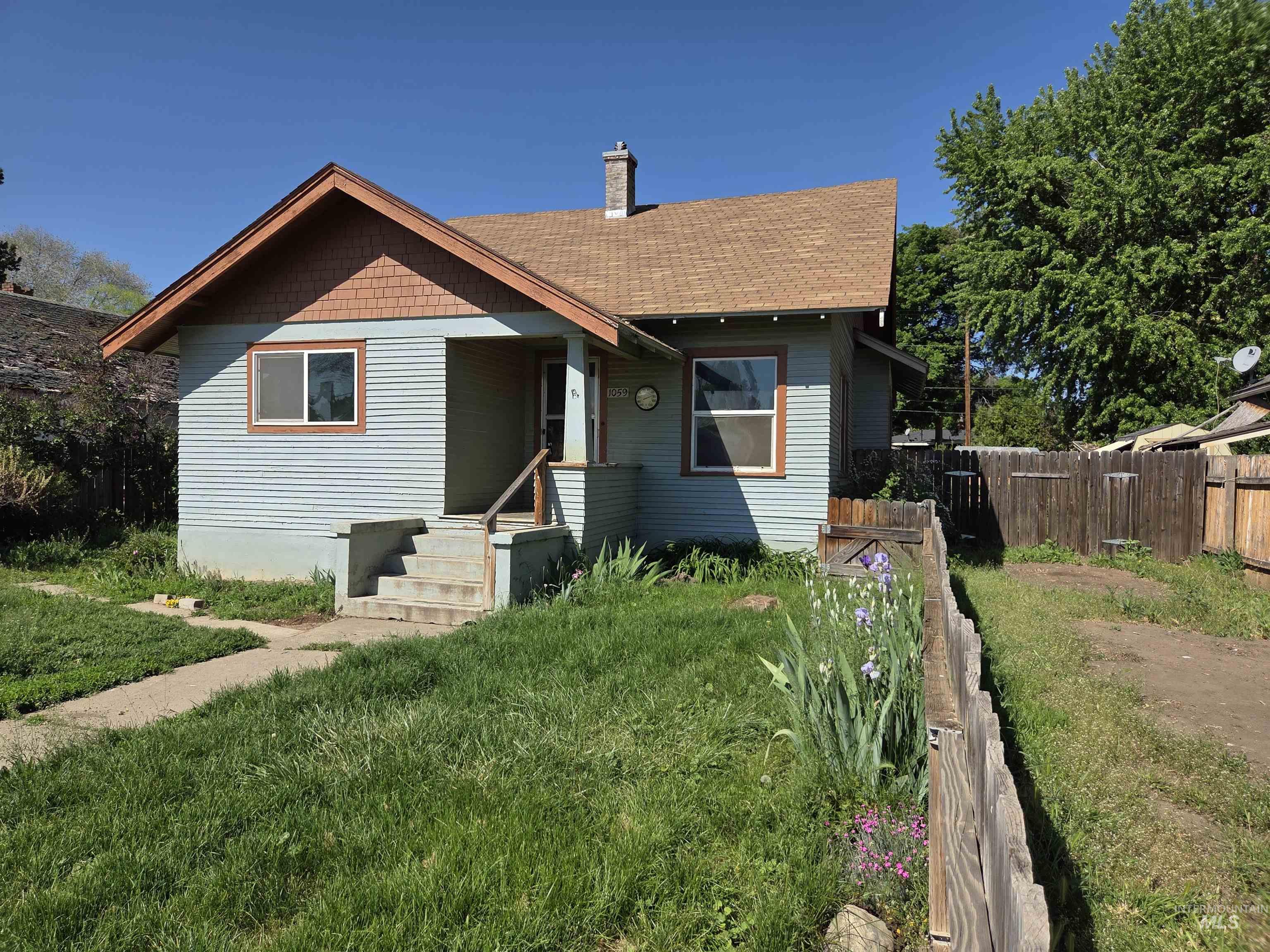 1059 State Street Weiser, ID 83672 - Photo 1 of 1 Single-story home featuring light blue horizontal siding and a brown shingle roof