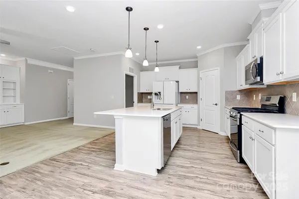a large kitchen with granite countertop a large counter top a sink stainless steel appliances and cabinets