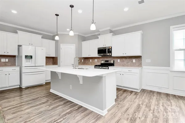 a kitchen with stainless steel appliances a stove top oven a sink dishwasher and a refrigerator with wooden floor