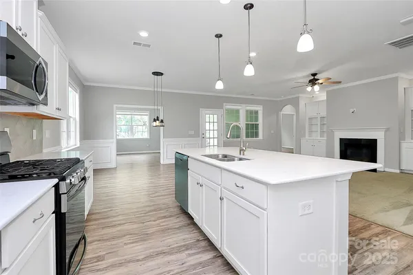 a large kitchen with kitchen island a stove a sink a center island and wooden floor