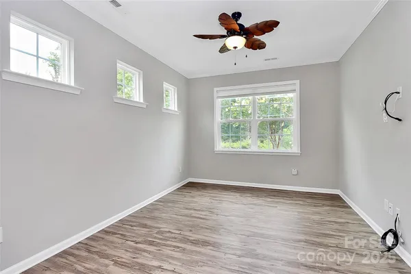 a view of room with window ceiling fan and wooden floor