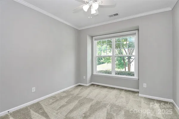 an empty room with a chandelier fan and windows