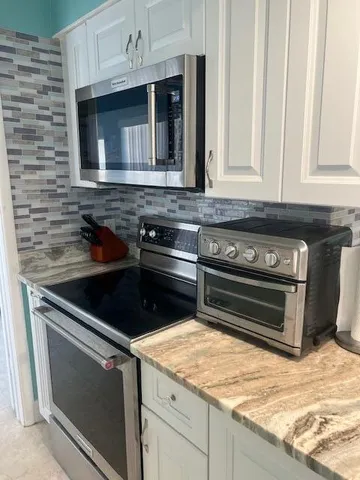 a kitchen with granite countertop a stove and a microwave