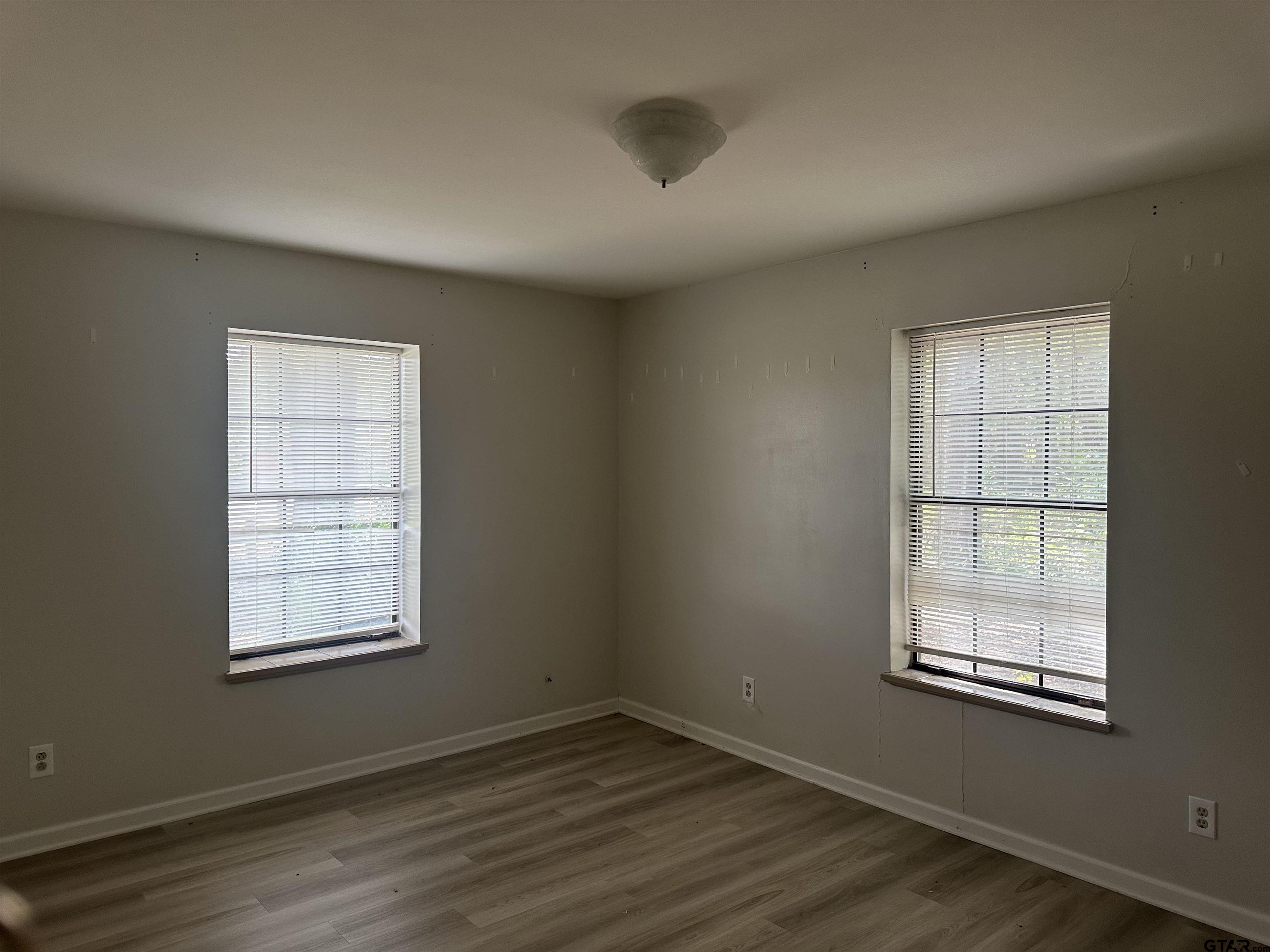 141 Meador Road Kilgore, TX 75662 - Photo 12 of 14 an empty room with wooden floor and windows
