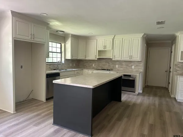 a kitchen with kitchen island granite countertop a sink stove and refrigerator