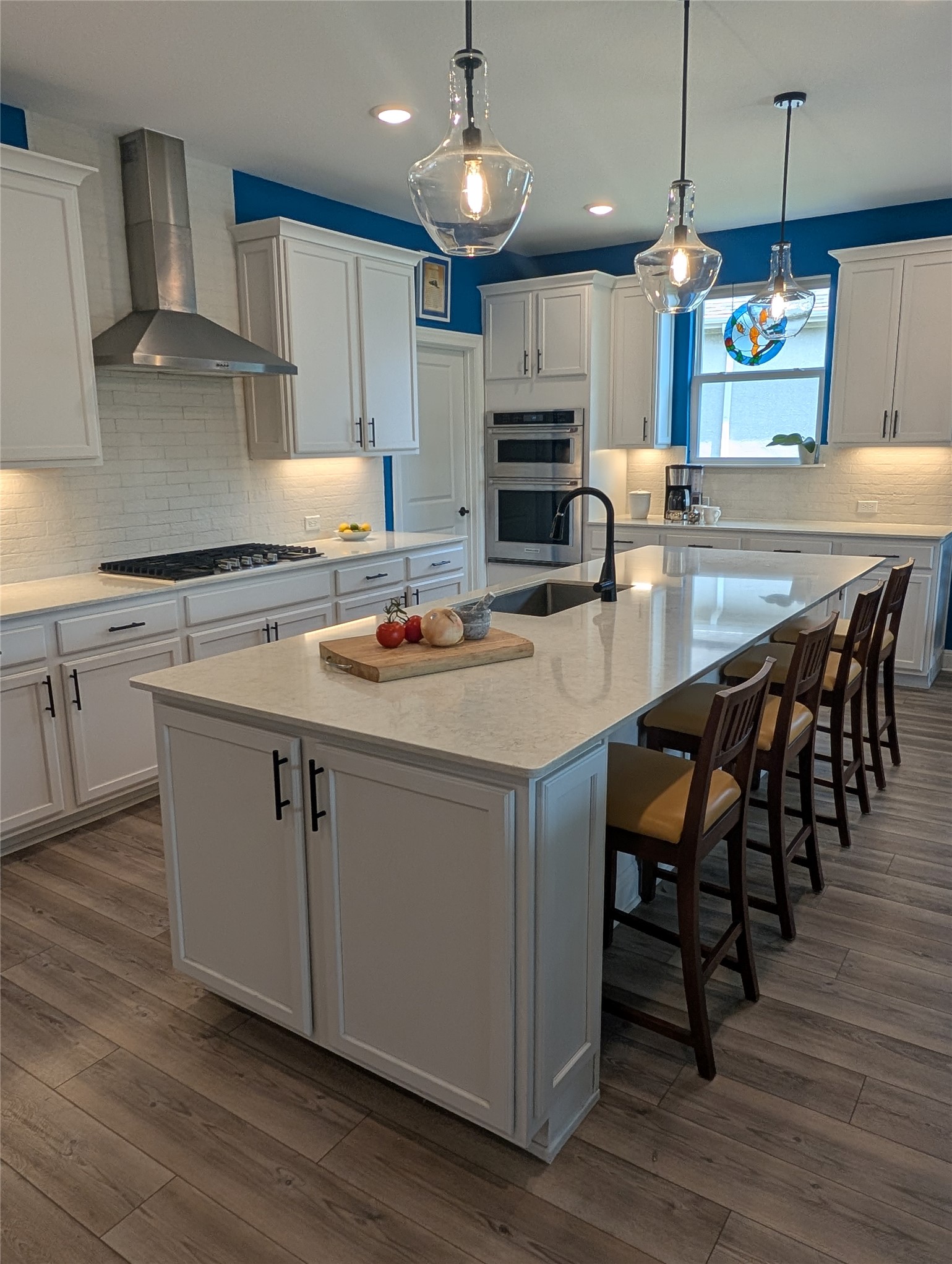 336 Kitty Hawk Road Georgetown, TX 78633 - Photo 15 of 40 An expansive central island anchors this modern culinary space featuring high-quality finishes and hardwood flooring.