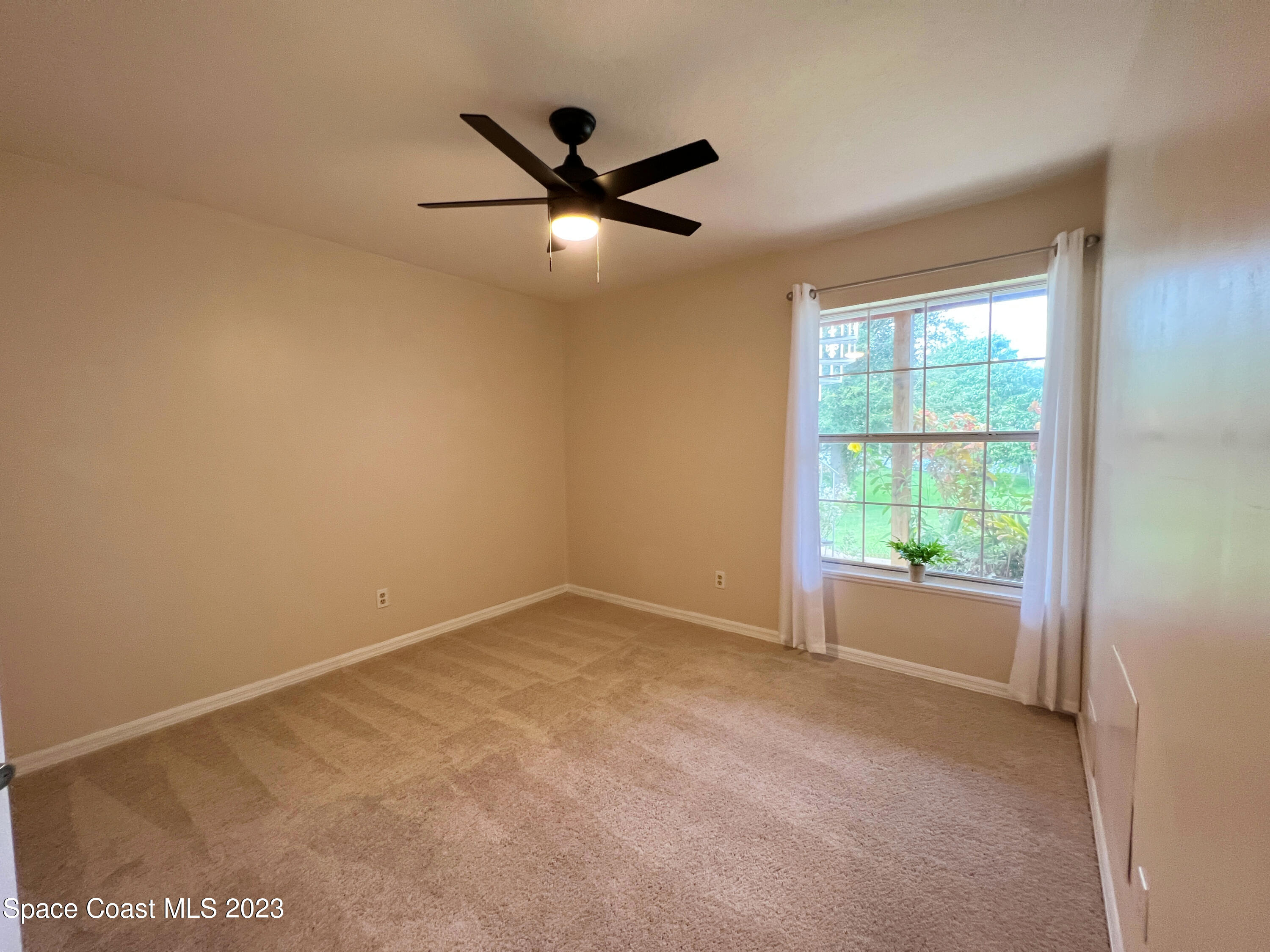 3475 Big Pine Road Melbourne, FL 32934 - Photo 21 of 28 an empty room with a ceiling fan and windows