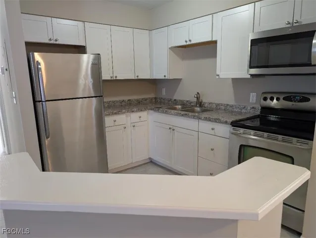 a kitchen with granite countertop a refrigerator stove a sink and dishwasher with wooden floor