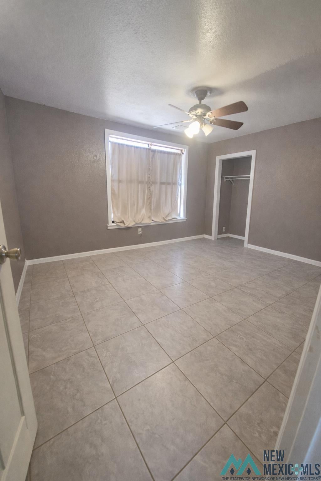 757 South Roosevelt Rd R 1/2 Portales, NM 88130 - Photo 14 of 14 Unfurnished room featuring a ceiling fan, light tile patterned floors, and a textured ceiling