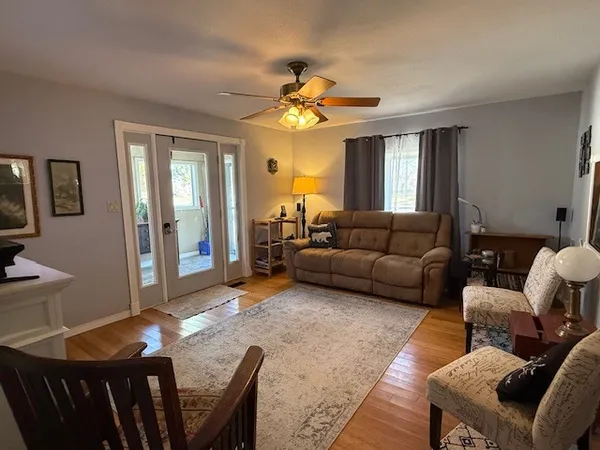 a living room with furniture a chandelier fan and a window
