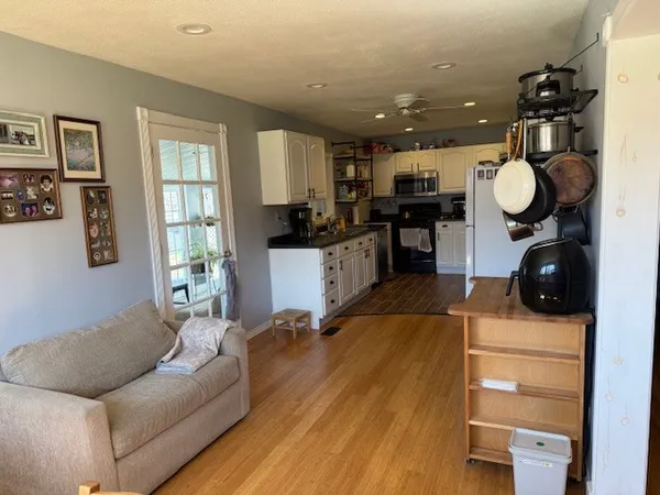 a living room with stainless steel appliances kitchen island granite countertop furniture and a wooden floor