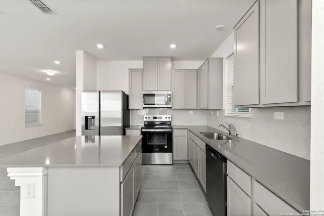 a kitchen with stainless steel appliances granite countertop a sink a stove and a refrigerator