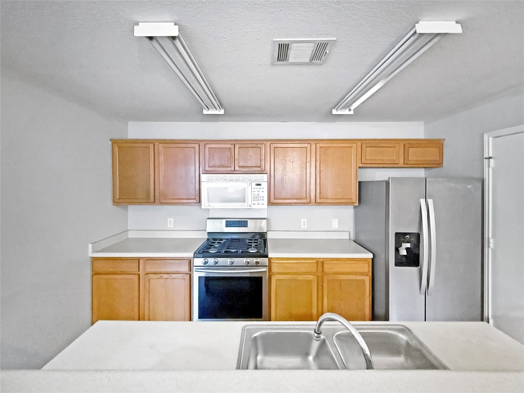 4516 Felicity Lane Austin, TX 78725 - Photo 6 of 15 a kitchen with a sink a stove and refrigerator