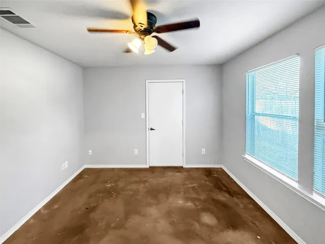 an empty room with a window and a fan