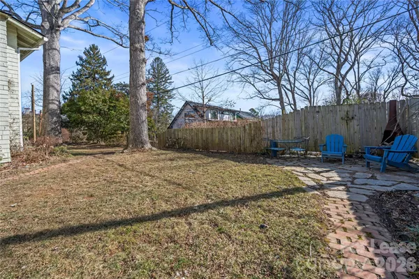a view of a backyard with potted plants and large trees
