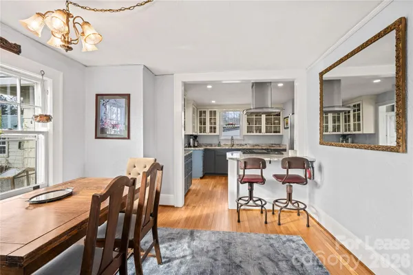 a dining room with wooden floor and chandelier