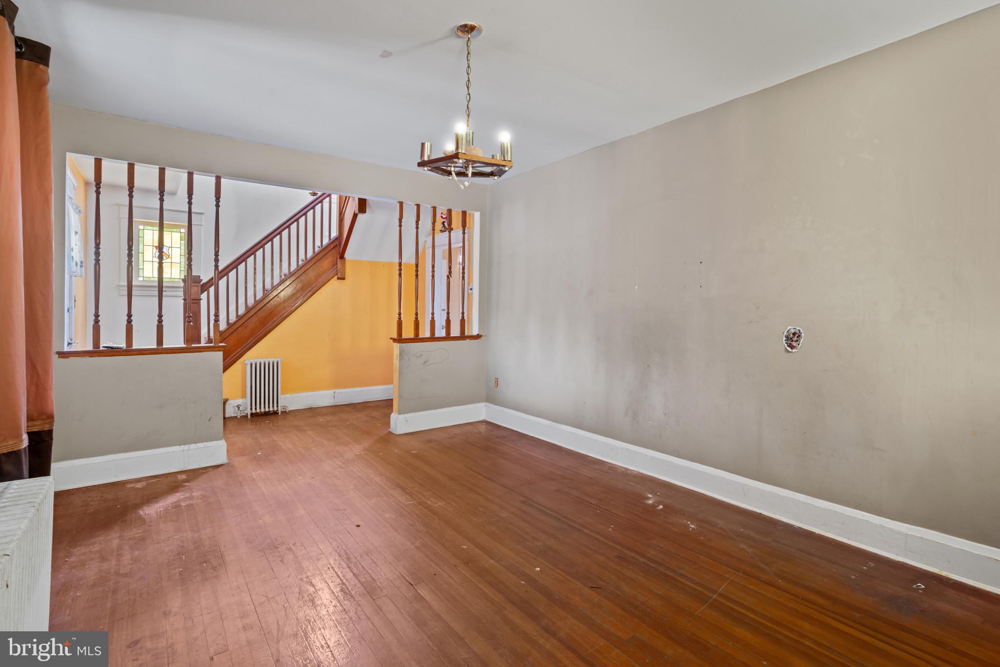 2908 Ailsa Avenue Baltimore, MD 21214 - Photo 7 of 29 a view of an empty room with wooden floor stairs and a chandelier