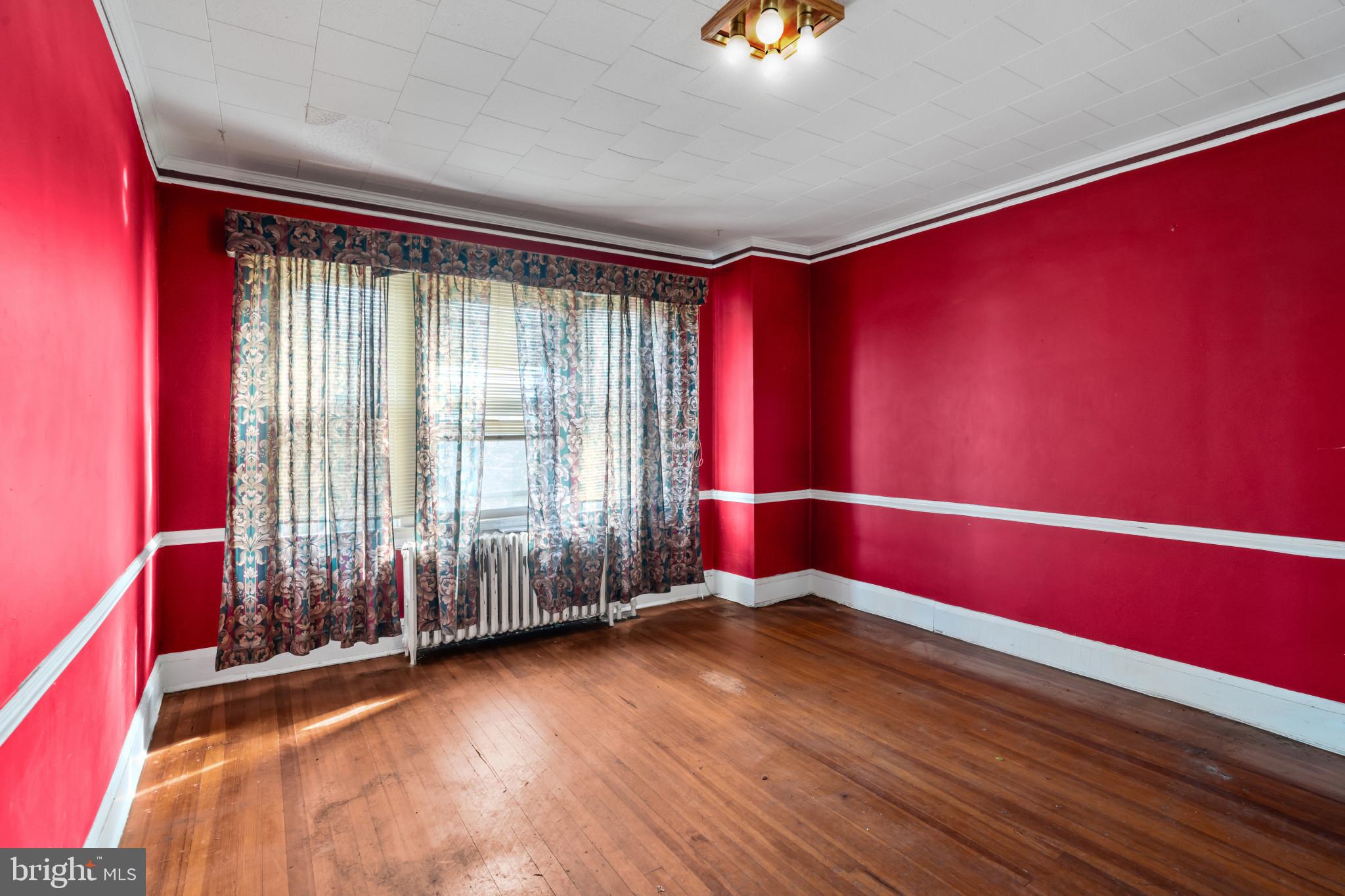 2908 Ailsa Avenue Baltimore, MD 21214 - Photo 8 of 29 an empty room with wooden floor and windows with curtains