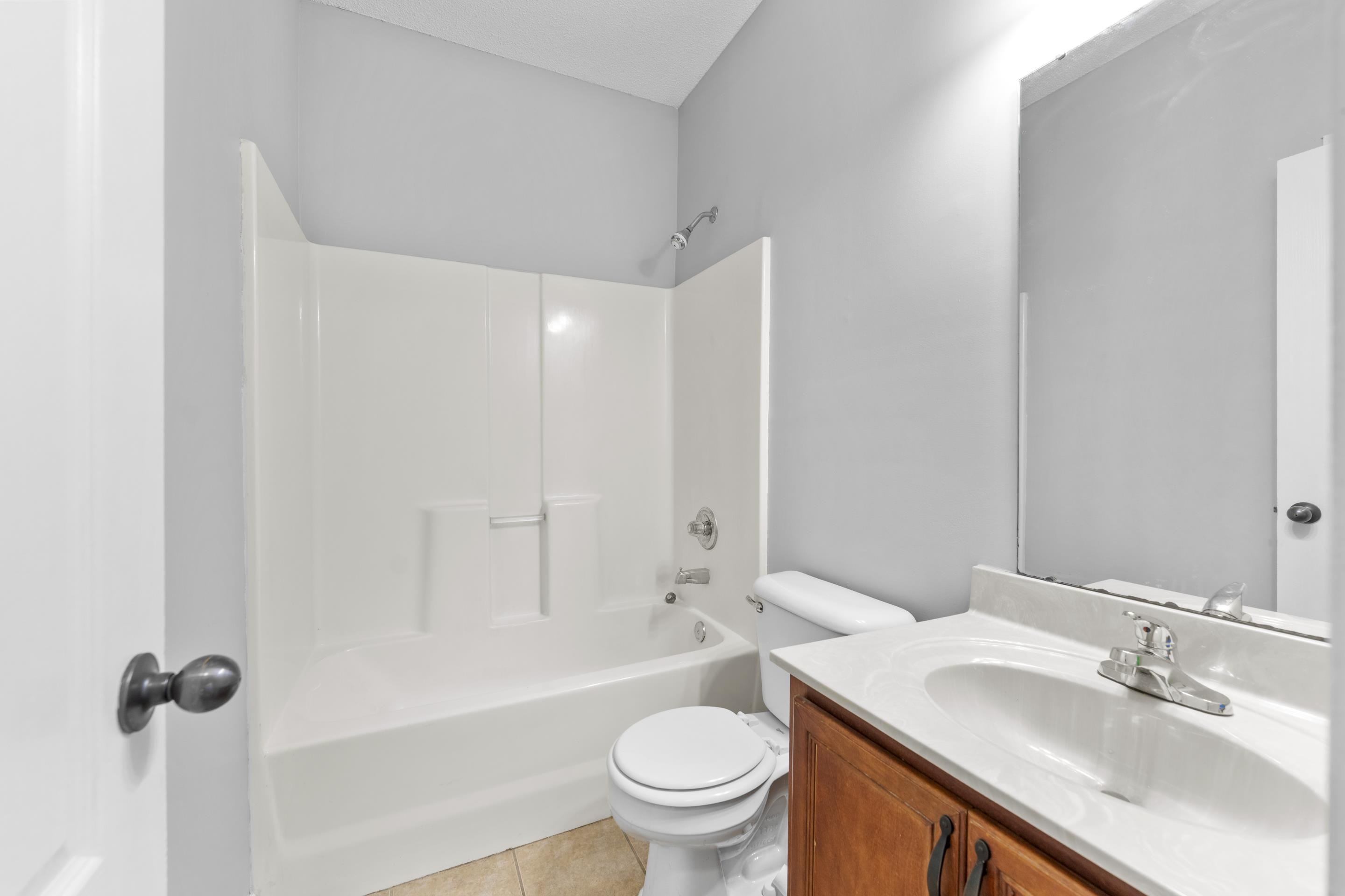 50 Abbey Road Oakland, TN 38060 - Photo 21 of 26 Bathroom featuring a white tub-shower combination, wood-finish vanity with a white countertop, ceramic tile flooring, and a large wall-mounted mirror