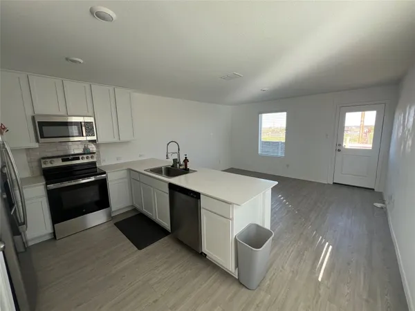 a kitchen with a sink a stove a refrigerator and white cabinets