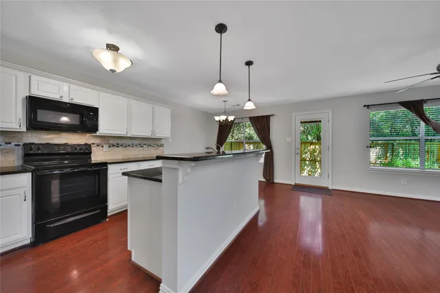 a kitchen with stainless steel appliances granite countertop a stove a refrigerator a sink a microwave a dining table and chairs with wooden floor