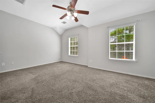 an empty room with windows and fan