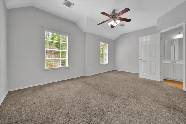 an empty room with windows and ceiling fan