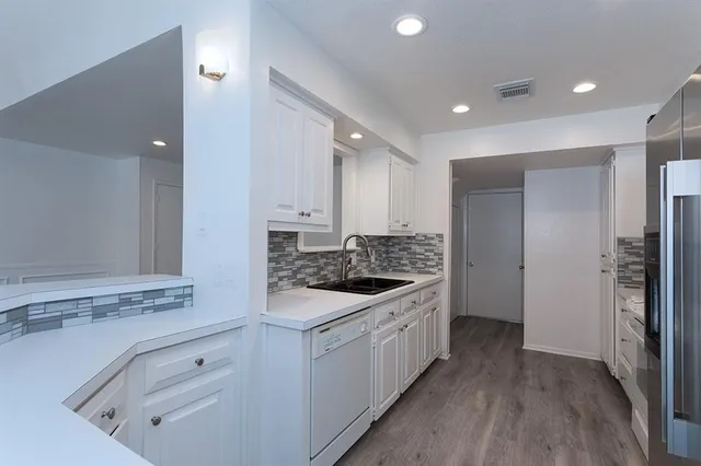 a kitchen with kitchen island white cabinets and stainless steel appliances