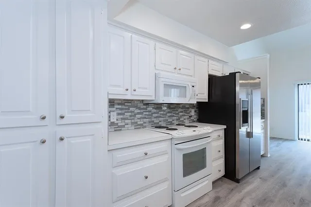 a kitchen with white cabinets and appliances