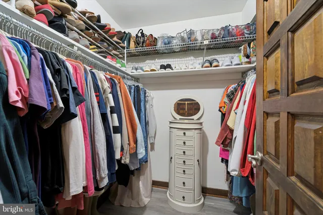 a view of walk in closet with clothes and shoes