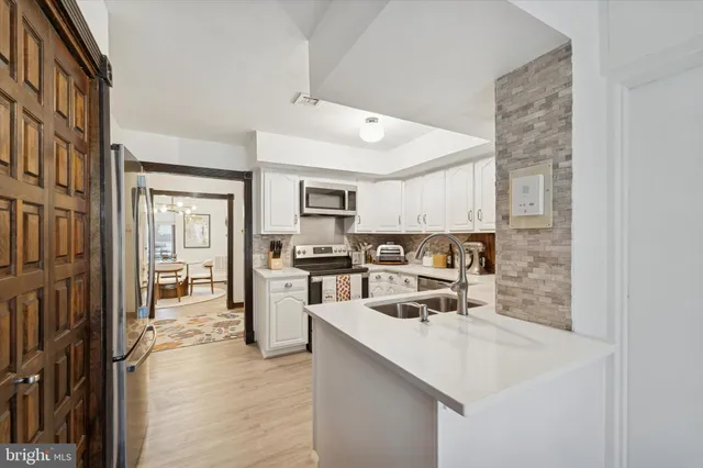 a kitchen with a sink a counter top space stainless steel appliances and cabinets
