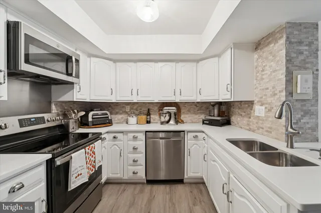 a kitchen with stainless steel appliances granite countertop white cabinets sink and stove